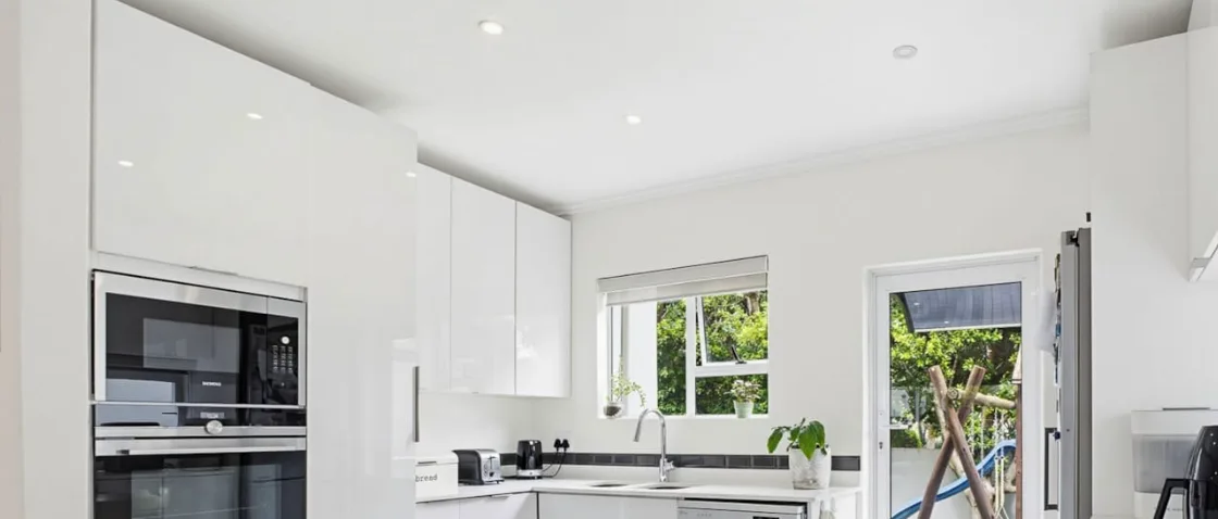White kitchen with built-in ovens and a microwave in a tall unit