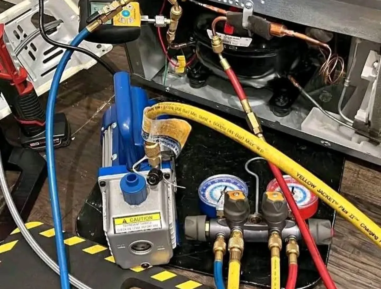 Vacuum pump and gauges connected to a refrigeration compressor during a commercial repair
