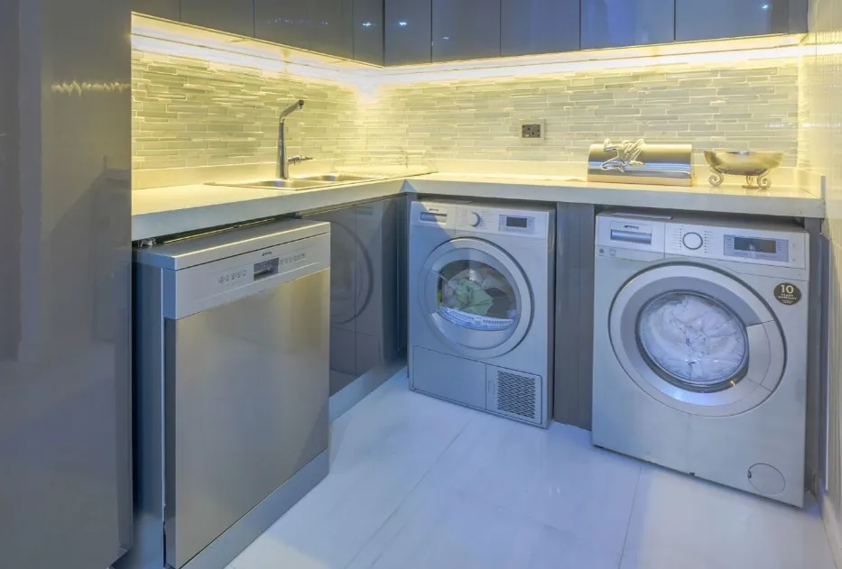 Stainless steel dishwasher installed next to a tumble dryer and washing machine