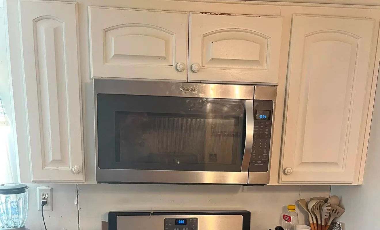 A microwave fitted between kitchen cabinets