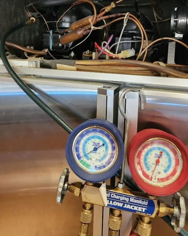Refrigerant pressure gauges connected to a fridge during a regas